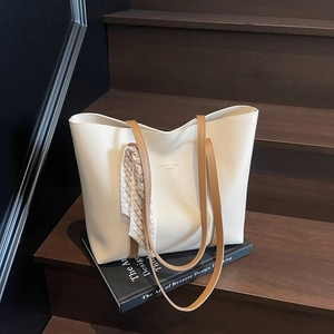 Minimalist off-white oversized tote bag with brown straps and scarf on a vintage staircase
