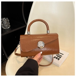 Close-up of brown square bag with large silver spherical lock and glossy finish