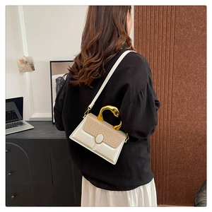 Detail of white leather crossbody bag with woven texture flap and gold snake handle