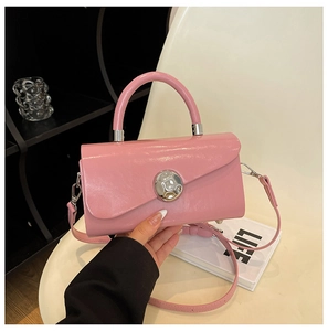 Close-up of pink glossy leather handbag featuring a prominent silver spherical metal lock