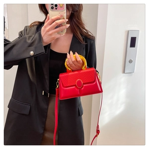 Detailed view of red contrast box bag featuring a large golden circular resin handle