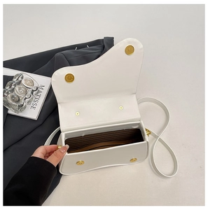 Detail view of white saddle bag opening with striped lining and gold magnetic clasps