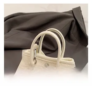 Close-up of white lychee leather handbag showing handle stitching and metal hardware