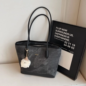 Minimalist grey textured tote bag with golden WWTU text and cute plush charm detail