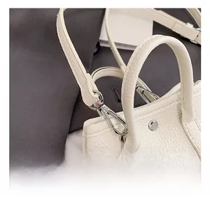 Detailed close-up of the silver metal hook and strap on white lychee leather handbag