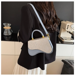 Detail of light blue saddle bag with snake pattern flap worn with a black blazer