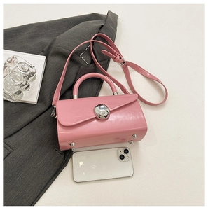 Detailed view of a pink glossy mini box bag with silver spherical buckle and metal studs