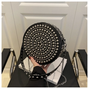 Close-up of a black circular crossbody bag featuring punk style silver rivet studs
