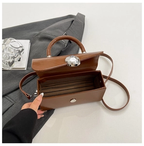 Detail of open brown box bag showing striped fabric lining and silver twist lock