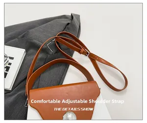 Detail of adjustable leather strap with silver buckle on a caramel crossbody bag