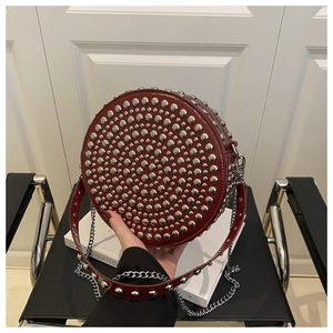 Macro detail of red round crossbody bag featuring silver stud rivets and a sleek chain