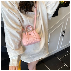 Lifestyle shot of a mini sakura pink bucket bag with leather texture and silver buckle
