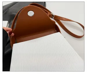 Close-up detail of the magnetic snap closure and leather texture on a brown saddle bag