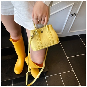 Detail of yellow lychee grain leather mini handbag with silver round buckle and handle
