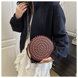 Detail view of burgundy round studded handbag with silver chain strap on model