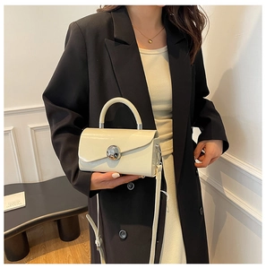 Detail of cream white glossy leather handbag with a silver ball-shaped metal buckle