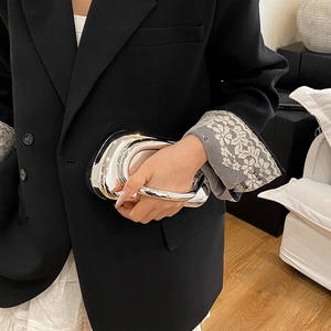Detail of silver metallic evening clutch with irregular organic shape and mirror finish