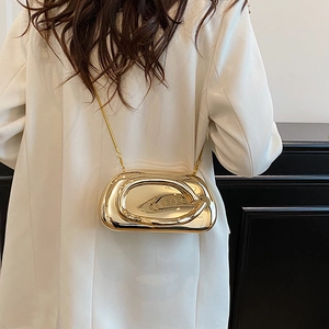 Detail of a luxury gold bean-shaped hard shell metal clutch bag with a slim chain strap