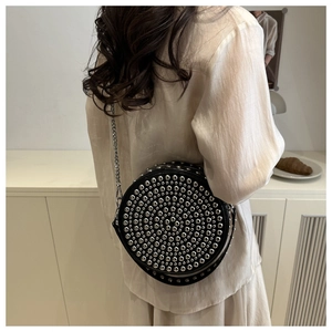 Detail view of round rivet crossbody bag showing the studded design and chain strap texture
