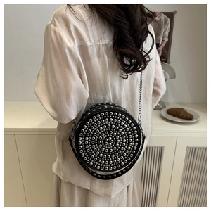 Detail of black round leather crossbody bag featuring silver rivet studs and chain strap