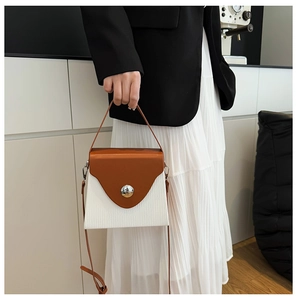 Detail of color-block crossbody bag featuring brown and white texture with silver buckle