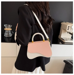 Detail of pink and white color-block crossbody bag with asymmetric wave design and gold hardware