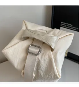 Detail of cream-colored canvas tote with thick handle and silver metal adjustment buckle