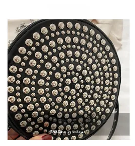 Detail shot of silver metal rivets on a black leather round crossbody bag
