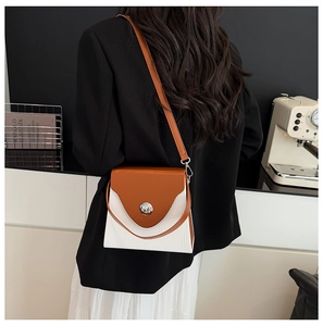 Detail of color-block shoulder bag featuring a brown flap and textured white body
