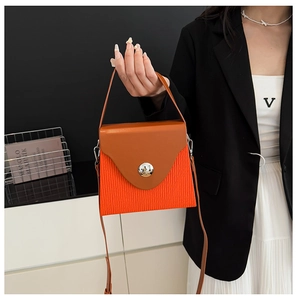 Detail of contrast color box bag with orange body and brown flap for fashion styling