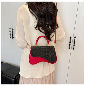 Detail of a snake-pattern flap handbag with a unique wavy base and contrast red leather