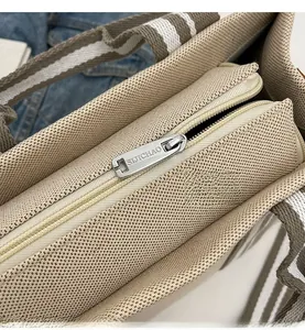 Détail de la fermeture éclair lisse et de l'anse rayée sur un cabas en toile beige