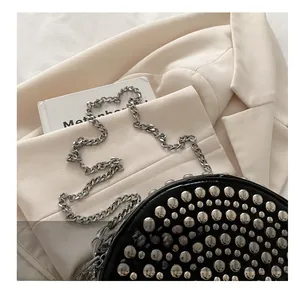 Detail of silver rivets and metallic chain strap on a black leather handbag