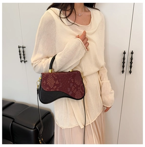 Detail of burgundy snakeskin texture and black panel contrast on mini saddle box bag