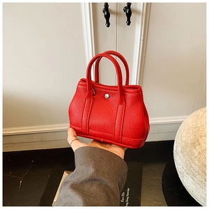 Detailed macro view of a red mini handbag in lychee leather with a silver buckle