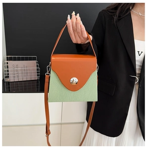 Close-up of contrast color handbag with orange leather handle and green textured body