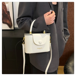 Detail of white PU leather box bag with gold round buckle and fashion logo lettering