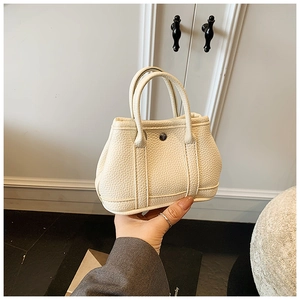 Detailed close-up of cream mini tote bag with litchi grain texture and metal buckle