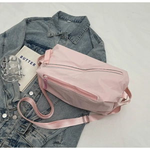Detailed close-up of pink nylon crossbody bag with metal buckle on white fabric