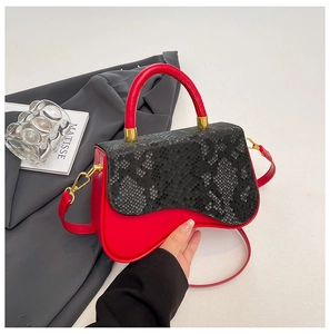 Detail of red and black snakeskin pattern crossbody bag with unique wavy base design