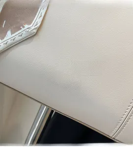Detailed close-up of cream textured leather tote with gold logo and stylish silk scarf