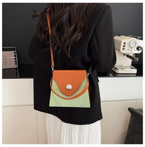 Detail of contrast color crossbody bag with orange leather flap and green pleated texture