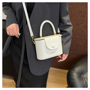 Detailed side view of white PU leather box bag with round top handle and golden hardware