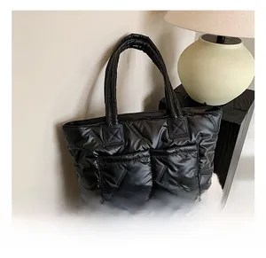 Detail of black quilted tote bag with front pockets and glossy padded material