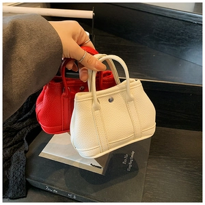 Close-up of mini lychee leather handbags in red and cream with metallic buckle detail