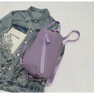 Detail of lavender nylon sling bag featuring wide straps and silver metallic zippers