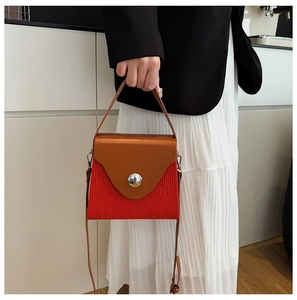 Detail of fashion crossbody bag with brown leather lid and red pleated texture contrast
