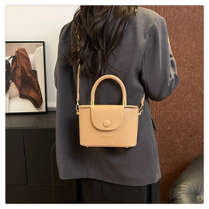 Close-up of beige box bag with top handle and FASHION & BAGS LEATHER print details