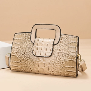 Detail of beige crocodile embossed tote bag with square handle and crossbody strap