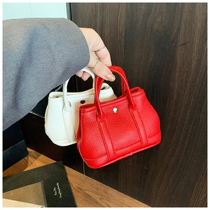 Close-up of mini leather handbags in red and white featuring litchi texture and round metal buckle